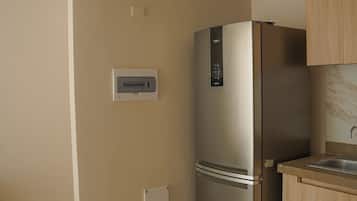 A kitchen with a stainless steel refrigerator, wooden cabinets, and a tiled floor.