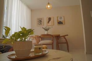 A dining area with a table, chairs, a potted plant, a candle, and wall art.