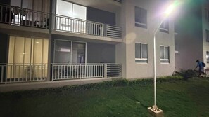 A multi-story building with balconies, a well-maintained lawn, and a street lamp.