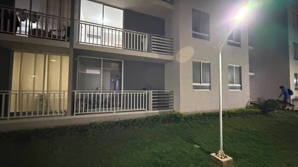 A multi-story building with balconies, a well-maintained lawn, and a street lamp.