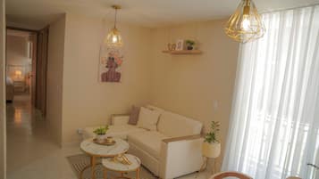 A modern living room with a beige sofa, two round tables, and decorative plants.