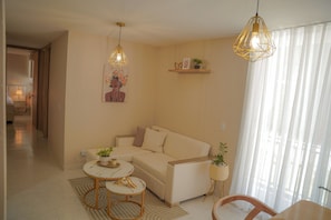 A modern living room with a beige sofa, two round tables, and decorative plants.