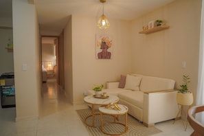 A living room with a sofa, a coffee table, a rug, and a painting on the wall.