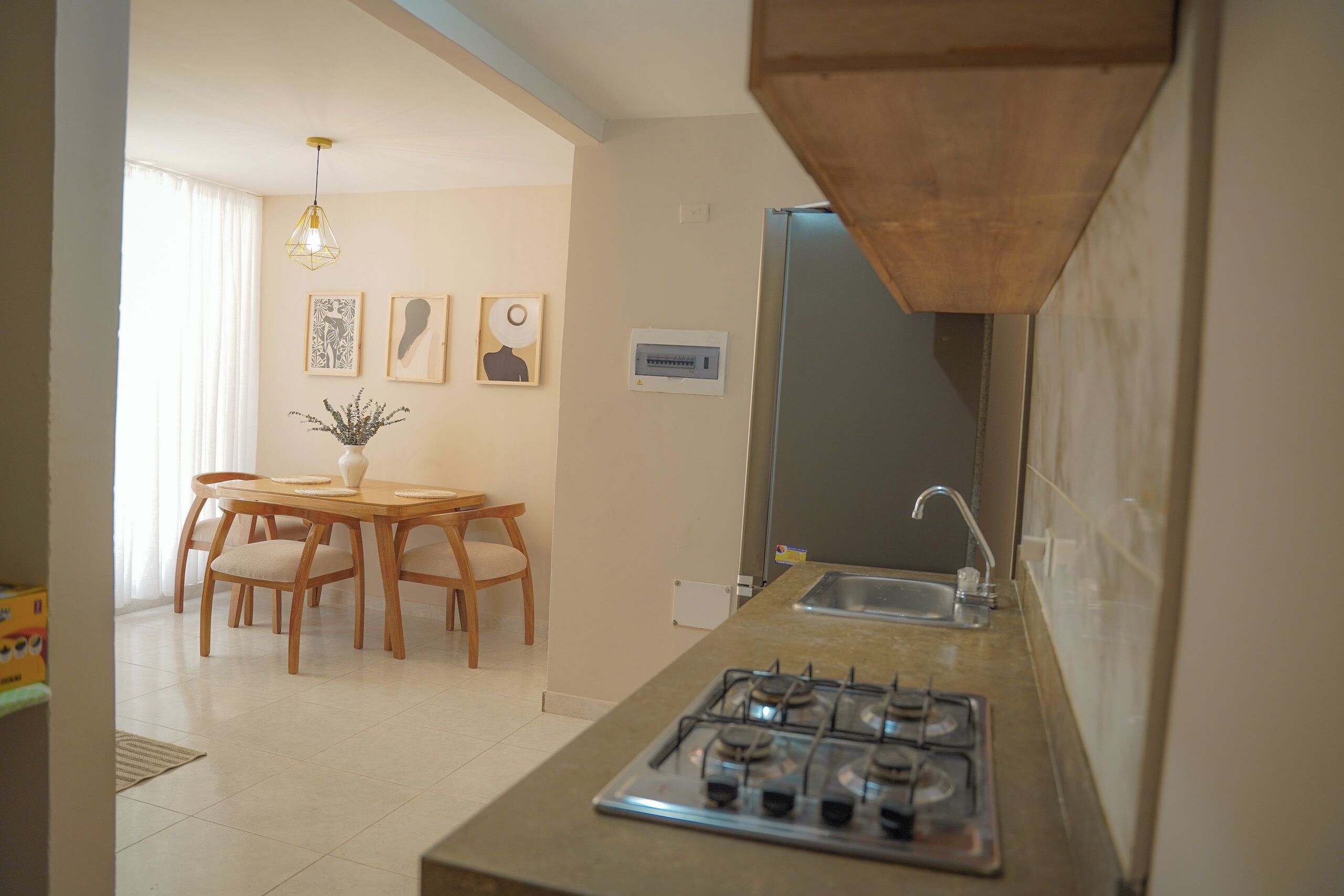 Une cuisine compacte équipée d’une cuisinière à gaz, d’un évier et d’un coin repas avec des chaises et une table.