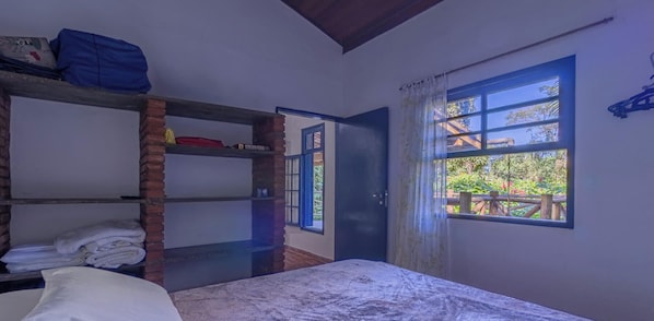 A room with a bunk bed, a single bed, a window with a view of greenery, and a door leading outside. - Casa em Ilhabela com Deck Privativo no Mar (sao sebastiao)