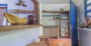 A compact kitchen with a sink, shelves, and a wooden table. - Casa em Ilhabela com Deck Privativo no Mar (sao sebastiao)