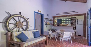 A cozy room with a striped sofa, a wooden table, and a large wheel. - Casa em Ilhabela com Deck Privativo no Mar (sao sebastiao)