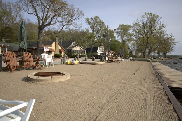 A beachside property with a wooden dock, a sandy beach, and a row of cabins.
