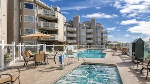 A pool area with lounge chairs and a building with balconies. - WM BLOCK Mariners Village 1br (Ocean Shores)
