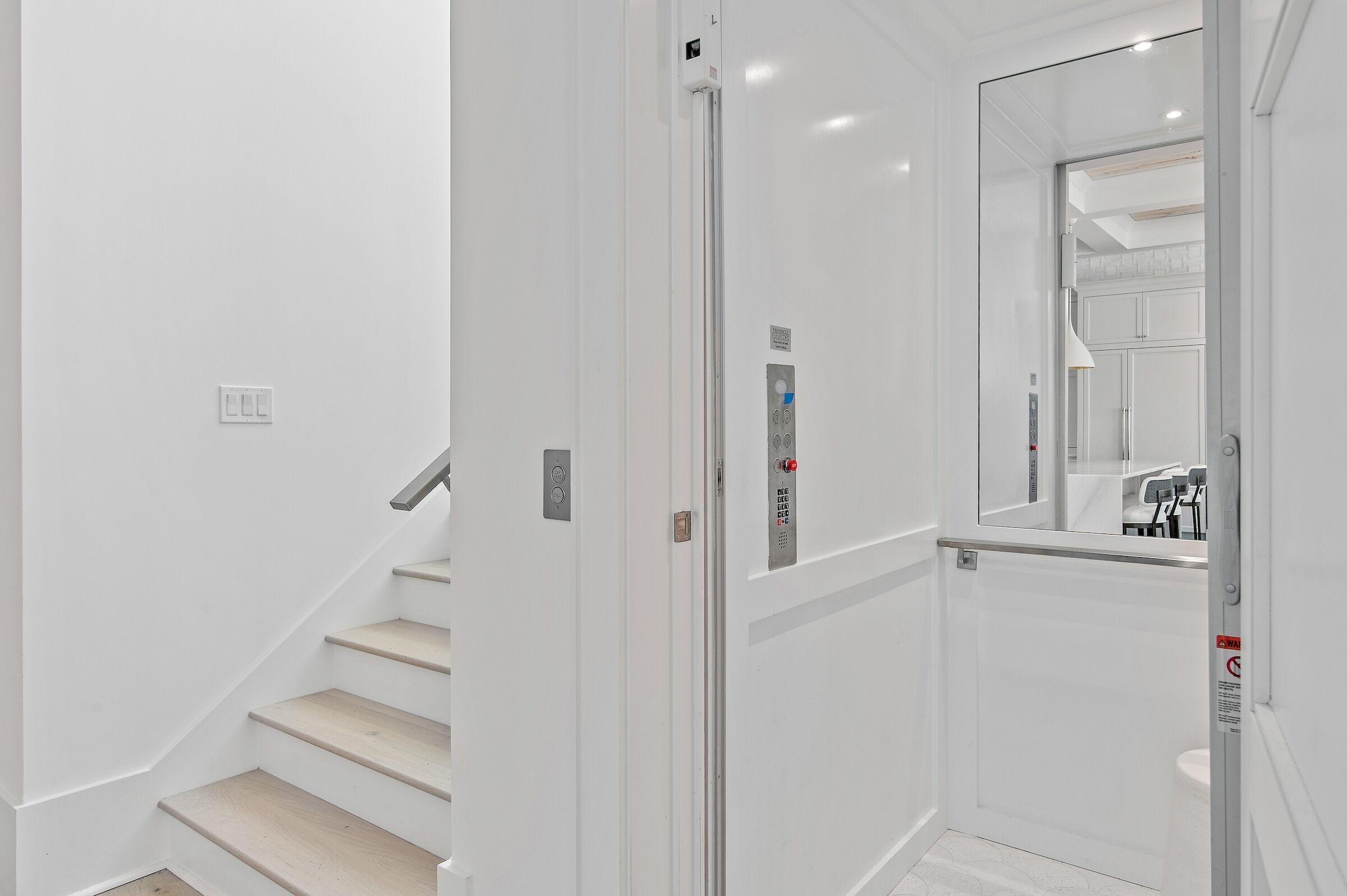 A modern elevator with a control panel and emergency buttons.