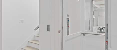 A modern elevator with a control panel and emergency buttons.