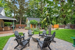 Une terrasse avec des fauteuils Adirondack, un foyer et un arbre aux fruits verts.