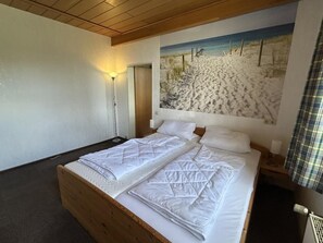 A double bed with a wooden headboard, a wall-mounted light, and a beach-themed mural. - NEW! "Ostfriesennest" Vacation Rental (Dunum)