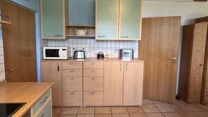 Cocina con armarios de madera, microondas y tostadora.