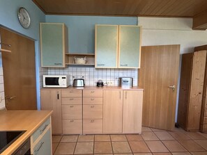 A kitchen with wooden cabinets, a microwave, and a toaster. - NEW! "Ostfriesennest" Vacation Rental (Dunum)