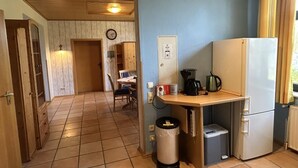 Cocina compacta con refrigerador, cafetera y contenedor de basura.