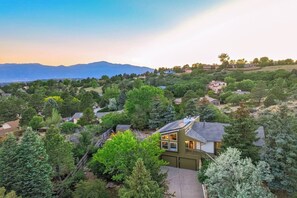 A residential area with houses surrounded by trees and a mountain range in the background. - 6BR Sleeps 14 · Two Living Areas, Game Room, Hot Tub, Mtn View (Colorado Springs)