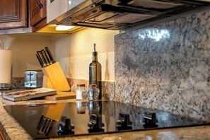 Een keuken met een marmeren aanrecht, een fles olijfolie, een zoutstrooier en een messenblok.