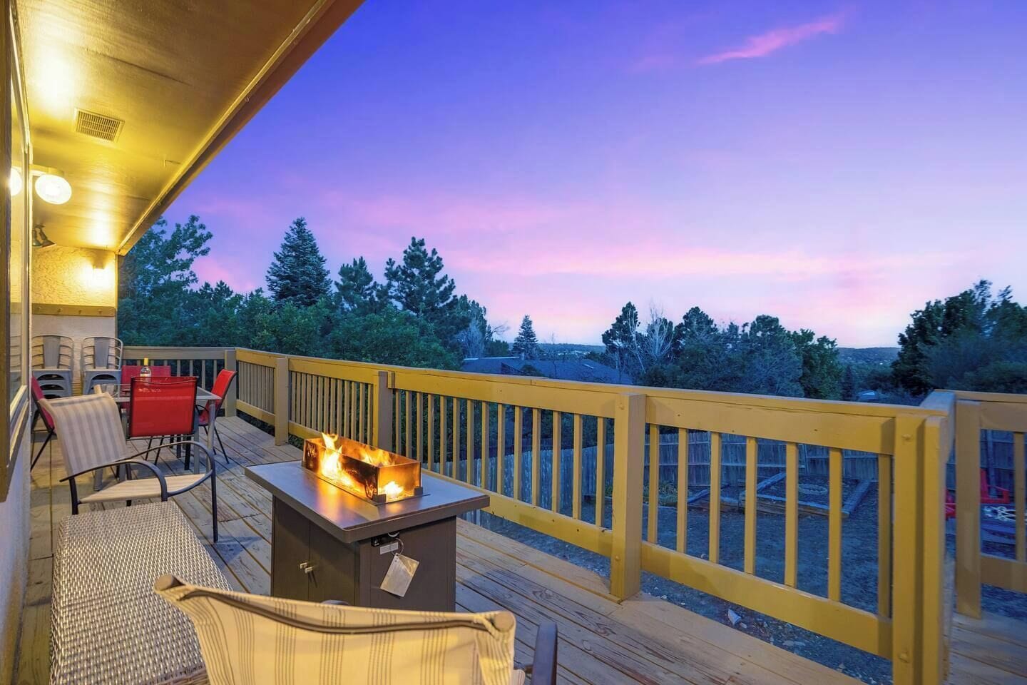 A deck with a fire feature, outdoor furniture, and a view of trees.