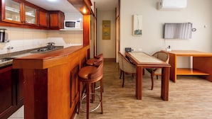 A kitchen with wooden cabinets, a microwave, a gas stove, and a bar area with stools. - Classic by Bhomy (São Paulo)