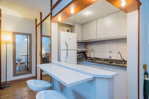Une cuisine moderne avec des armoires blanches, un four à micro-ondes encastré et une cuisinière à gaz.