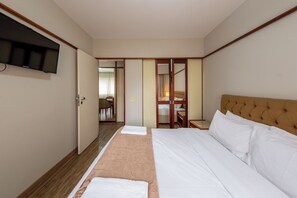 A hotel room with a bed, a television, a desk, and a chair. - Classic by Bhomy (São Paulo)