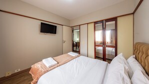 A hotel room with a bed, a television mounted on the wall, and a mirror with a wooden frame. - Classic by Bhomy (São Paulo)