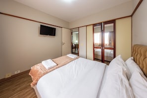 A hotel room with a bed, a television mounted on the wall, and a mirror with a wooden frame. - Classic by Bhomy (São Paulo)