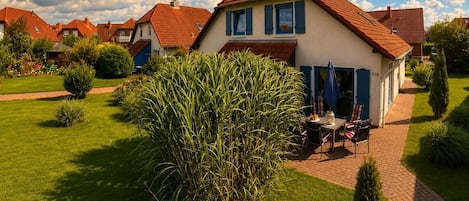 Il s’agit d’une propriété résidentielle dotée d’une pelouse bien entretenue, d’une terrasse avec mobilier d’extérieur et d’une maison dont le toit est recouvert de tuiles rouges.