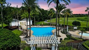 A resort with a large swimming pool, palm trees, and a golf course in the background. - 3BR Reunion Resort Pool & Golf Views Near Disney (Kissimmee)