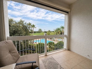 A balcony with a view of a swimming pool and palm trees. - 3BR Reunion Resort Pool & Golf Views Near Disney (Kissimmee)