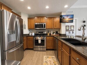 A modern kitchen with stainless steel appliances, wooden cabinets, and a granite countertop. - Reunion Resort 3BR | Beautiful Views + Pool Access (Kissimmee)