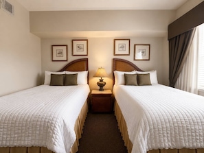 A hotel room with two beds, a nightstand with a lamp, and framed pictures on the wall. - 3BR Reunion Resort Pool & Golf Views Near Disney (Kissimmee)