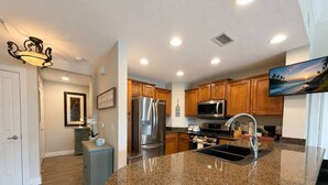 A modern kitchen with granite countertops, stainless steel appliances, and wooden cabinets. - 3BR Reunion Resort Pool & Golf Views Near Disney (Kissimmee)