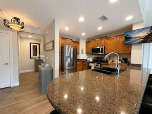 A modern kitchen with granite countertops, stainless steel appliances, and wooden cabinets. - 3BR Reunion Resort Pool & Golf Views Near Disney (Kissimmee)