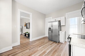 A modern kitchen with a stainless steel refrigerator, white cabinetry, and a wooden floor. - Roadmap Lodging: Solo Traveler 1BR, Own Entrance (Columbus)
