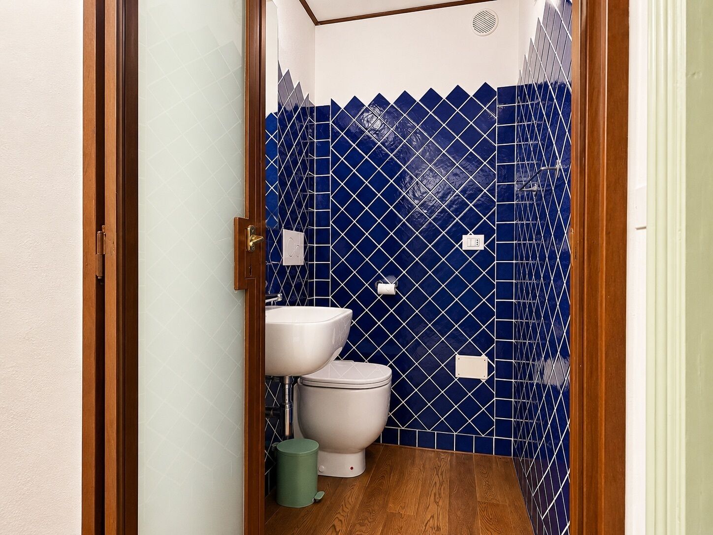 Un baño pequeño con inodoro, lavamanos y cubo de basura.