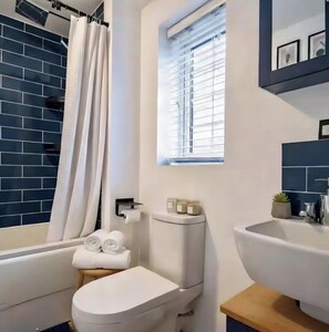 Een moderne badkamer met een wit toilet, een wastafel en een bad.