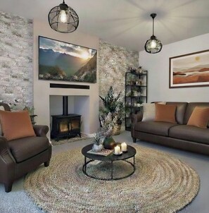 Ein Wohnzimmer mit Kamin, zwei Sofas, einem Couchtisch mit Kerzen und einem großen Gemälde an der Wand.
