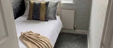 A narrow room with a bed, a window, and a radiator.
