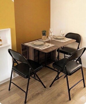 Ein Essbereich mit einem Holztisch, vier schwarzen Stühlen und einem kleinen Blumentopf.