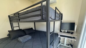 Una cama literera con escritorio y televisor en una habitación.