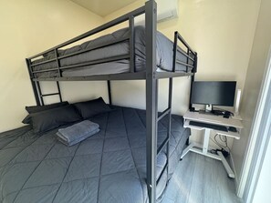 Una cama literera con escritorio y televisor en una habitación.