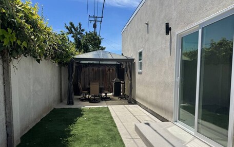 A backyard with a patio, a covered seating area, and a lawn.
