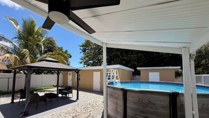 Et overdækket udendørs område med en pool, en pavillon og en stige ned til poolen.