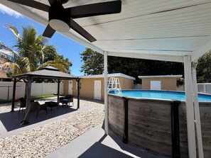 A covered outdoor area with a pool, a gazebo, and a ladder leading to the pool. - Cozy Poolside Guest House-Gazebo + Free Parking (West Park)