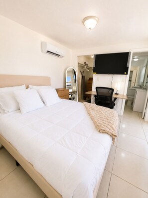 A hotel room with a bed, a desk, a chair, a TV, and a mirror. - Cozy Poolside Guest House-Gazebo + Free Parking (West Park)