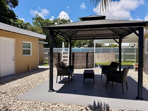 A covered patio area with outdoor furniture, a ladder, and a wooden fence in the background. - Cozy Poolside Guest House-Gazebo + Free Parking (West Park)