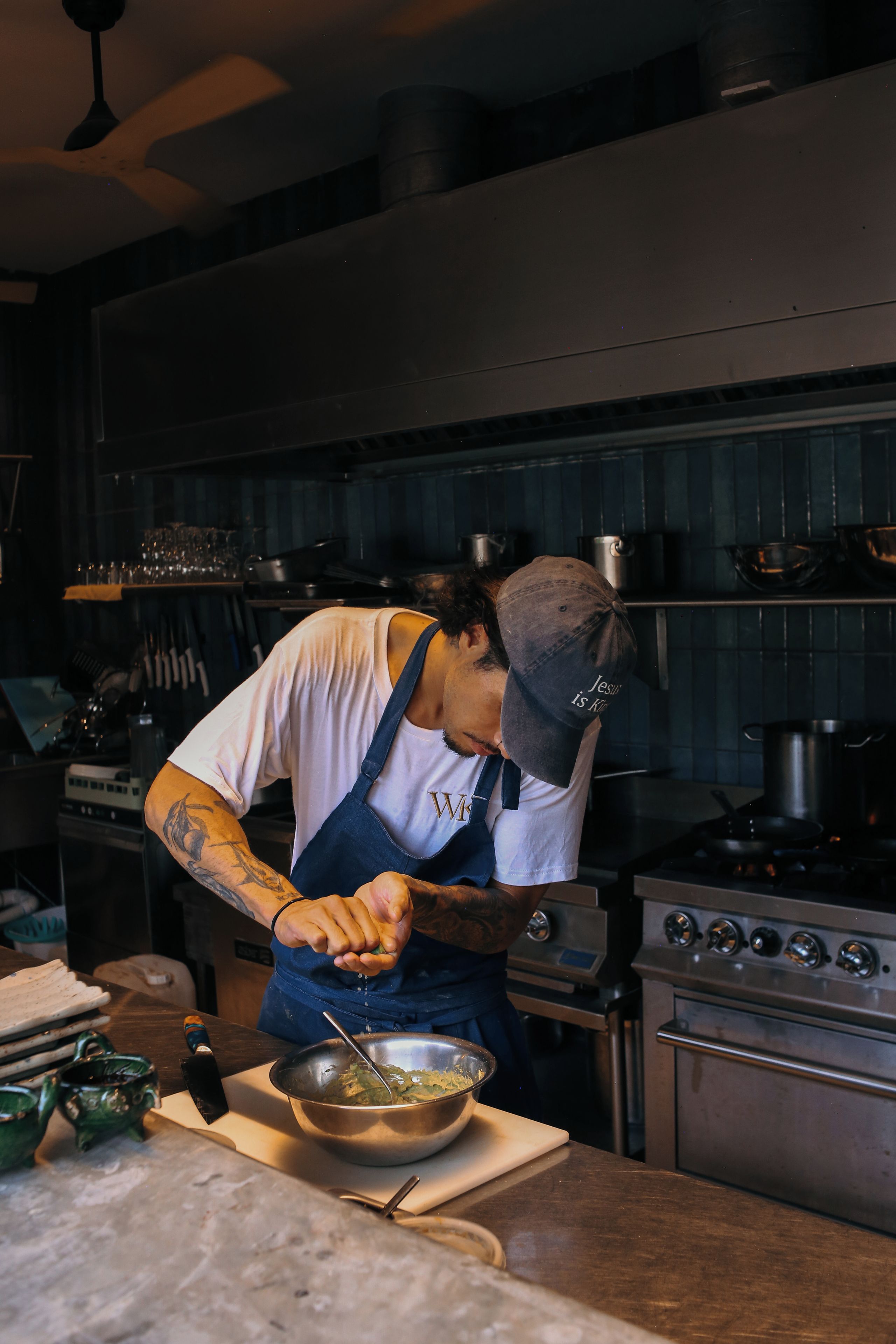 A chef preparing food in a kitchen with stainless steel appliances and a tiled backsplash.