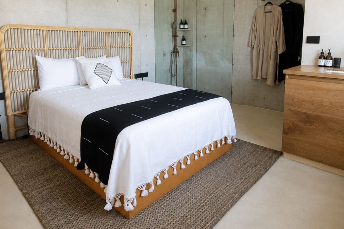 Un dormitorio moderno con cama, ducha y cómoda de madera.